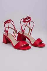 Sandalias rojas de cuero con tiras finas para atar al tobillo y tacón cuadrado.