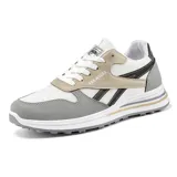 Zapatillas deportivas de estilo retro, color negro con detalles en beige claro y gris. Presentan una capellada de malla y superposiciones de material sintético, cordones negros y una suela gruesa con capas grises.