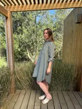 Vestido camisero blanco de lino, con cuello camisero, manga larga con botón para recoger, cierre frontal con botones de nácar, bolsillo en el pecho y diseño asimétrico más largo en la parte trasera.