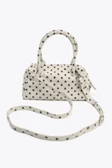 Bolso tipo bowling color crudo con estampado de lunares negros. Tiene doble asa de mano y correa bandolera extraíble. Incluye bolsillo interior con cremallera y cierre principal con doble cremallera.