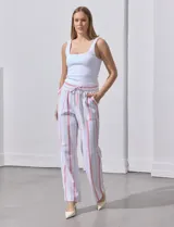 Pantalón de lino a rayas verticales color beige y blanco, con pretina ancha elastizada, lazo de ajuste y bolsillos inclinados.