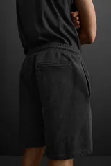 Bermuda jogger negra confeccionada en tejido de algodón con interior de rizo, cintura elástica ajustable con cordón y bolsillos laterales.