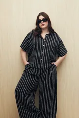 Pantalón ancho de viscosa con estampado a rayas verticales blancas sobre fondo negro, cintura elastizada y caída fluida.