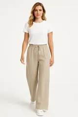Pantalón de lino color beige, de corte ancho y tiro alto, con bolsillos laterales y cintura elastizada con cordón ajustable.