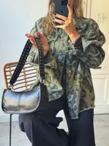 Campera de jean color beige con estampado animal print en tonos marrón y negro. Tiene cuello clásico, cierre frontal con botones, bolsillos con solapa y detalle de flecos en los bordes.