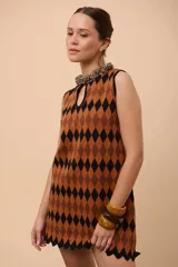 Vestido corto sin mangas con estampado de rombos en amarillo, azul y rojo. Tiene escote con abertura en forma de gota y ruedo con terminación en picos.