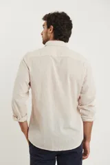 Camisa azul marino de lino y algodón, con cuello abotonado, manga larga con puños enrollados, bolsillo de parche en el pecho y cierre frontal con botones.