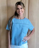 Remera de manga corta color celeste con pespuntes y bolsillo frontal, de corte holgado y larga en la parte posterior.