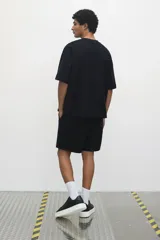 Remera negra de punto de algodón pesado, corte oversized, con cuello redondo ribeteado, hombros caídos y bajo recto.