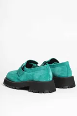 Mocasín de gamuza color verde oliva, con tira superior y suela track gruesa y negra.