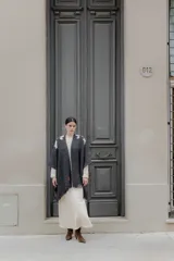Ruana gris con diseño de lunas blancas en los hombros y flecos en el borde inferior.