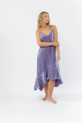 Vestido midi color lila metálico de breteles finos regulables, escote en V y ruedo asimétrico con leve vuelo.