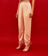 Pantalón jogger color beige de satín, con cintura elástica y lazos ajustables en los tobillos.