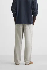 Pantalón color arena de corte recto, confeccionado en tejido de algodón y lino. Cuenta con cintura elástica ajustable con cordón, bolsillos delanteros y traseros de parche.