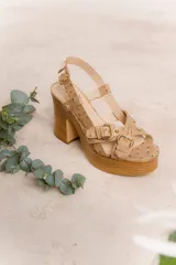 Sandalias de cuero negro con plataforma de madera y taco ancho. Presentan tiras anchas cruzadas sobre el empeine con hebillas doradas ajustables y pulsera al tobillo con hebilla.
