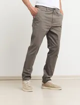 Pantalón largo de gabardina color verde medio, con corte slim fit y tobillos ajustados.