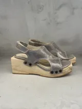 Sandalias plateadas con plataforma de madera, tiras de cuero y detalle de tachas. Hechas a mano en Uruguay.