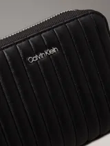 Billetera Calvin Klein negra acolchada con cierre de cremallera, logo plateado en el frente, cuatro ranuras para tarjetas, dos ranuras de seguridad, billetero y bolsillo monedero.
