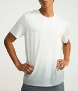 Remera deportiva blanca de poliéster y elastano, con cuello redondo, manga corta y estampa degradé.