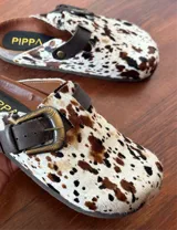 Zuecos con capellada de cuero con estampado animal print en tonos marrones y negros, con hebilla metálica color bronce y suela de goma.