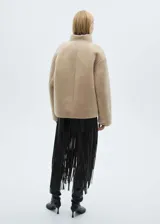 Chaqueta de pelo color beige con cuello alto, cierre frontal con botones y bolsillos delanteros.
