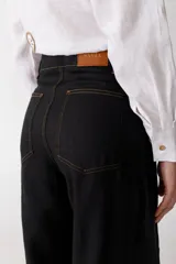 Pantalón de lino color crudo con finas rayas verticales negras, corte wide leg y tiro alto.