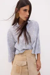 Camisa celeste a rayas verticales blancas con bordado de flores blancas, de corte recto y mangas 3/4.