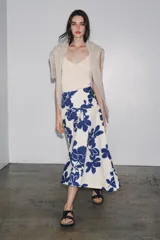 Falda midi de tiro medio confeccionada en hilatura de algodón, color blanco con estampado de flores azules. Cierre lateral con botones.
