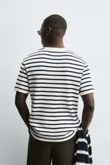 Camiseta de hombre de manga corta, color blanco con rayas horizontales azul marino. Confeccionada en tejido con estructura waffle y corte relaxed fit.