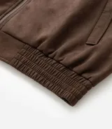 Campera marrón con cierre frontal, cuello inglés, bolsillos laterales y bajo con elástico. Presenta detalles de recortes en la parte superior. Marca Marfinno.