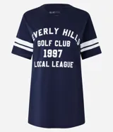 Remera azul marino de algodón con cuello en V y mangas cortas con rayas blancas. Estampa frontal con texto "Beverly Hills Golf Club 1997 Local League" en blanco.