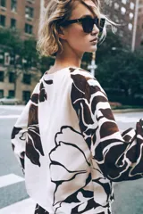 Blusa de cuello redondo y manga larga ancha con botones en los hombros. Estampado floral en tonos marrón y blanco.