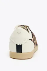 Zapatillas deportivas con estampado animal, suela color caramelo y cordones blancos.