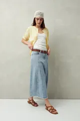 Falda midi de denim negro con tiro bajo, corte evasé, costuras verticales y ruedo desflecado.