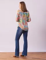 Blusa de gasa estampada con rayas verticales en tonos celeste, azul y blanco. Tiene cuello a la base con escote en V y abertura con botones. Las mangas largas son de largo regulable.