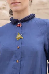 Vestido camisero azul de largo midi, con cuello mao con volados y mangas 3/4. Tiene cierre frontal con botones y un bolsillo de crochet aplicado.