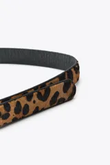 Cinturón fino de cuero con estampado animal print y hebilla rectangular dorada.