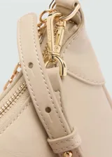 Bolso tipo baguette color beige, con asa corta de cadena dorada y cierre de cremallera superior.