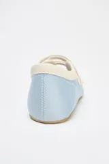 Zapato tipo bailarina deportiva color celeste con efecto satinado, puntera redondeada, suela plana y doble tira con ajuste adhesivo.