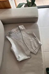 Chaleco plateado de cuero ovino, con cuello en V y sin cierre.