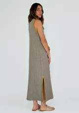 Vestido largo a rayas verticales color gris y blanco, con cuello en V y ribete amarillo. Presenta aberturas laterales con ribete amarillo.