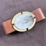 Cinto de cuero color camel con hebilla ovalada de bronce y pieza central de cuerno pulido.