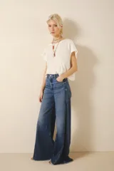 Pantalón jean corte oxford amplio de tiro medio, con cintura y cadera ajustada y piernas que se ensanchan desde la cadera hacia los tobillos con recortes en los laterales que le da un vuelo mayor a la pierna. Tejido rígido azul con lavado stone, localizado y bigotes. Con cierre y botón.