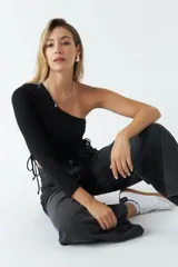 Top asimétrico blanco de una sola manga con jaretas ajustables en ambos lados del torso para regular el largo.