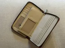 Billetera rectangular de cuero color naranja con cierre de cremallera y diseño geométrico en relieve.