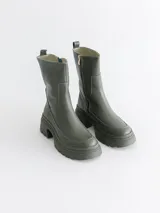 Bota corta color verde militar, con caña media, suela track y elástico lateral.