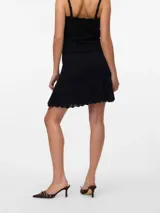 Pollera tejida de algodón y poliéster, color negro, de tiro medio, con textura de punto plano y ruedo con volado.