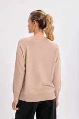 Buzo básico de tejido de punto color beige, con cuello redondo y mangas largas.