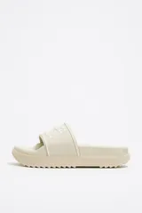 Sandalia tipo ojota color beige con plataforma y logo de la marca en la tira superior.