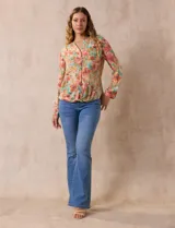 Blusa de gasa estampada a rayas verticales en tonos celeste, lila, naranja y marrón. Tiene cuello a la base con escote en V y botones. Delantera con bolsillo aplicado. Largo de manga regulable con presilla y botón. Terminación anudada opcional.
